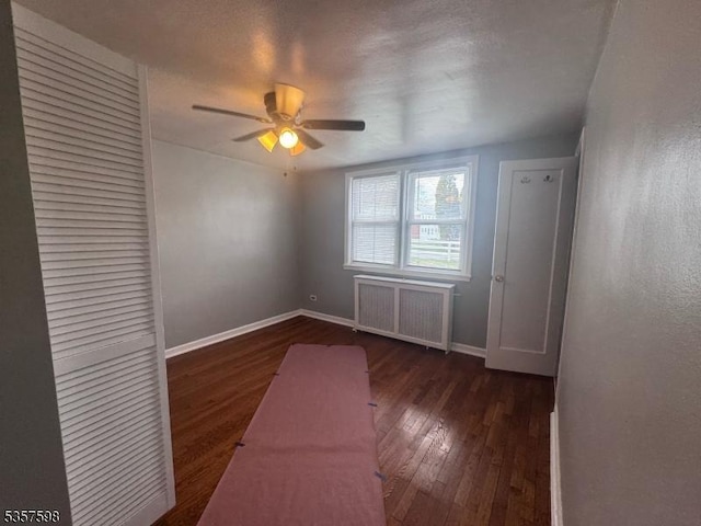 unfurnished bedroom with radiator heating unit, hardwood / wood-style floors, baseboards, and a ceiling fan