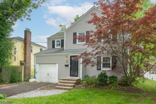 view of front of home with driveway, a shingled roof, and a garage