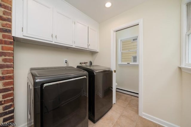 washroom featuring a baseboard heating unit, cabinet space, washer and clothes dryer, light tile patterned floors, and baseboards