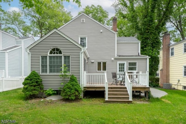 back of house with a lawn, a wooden deck, a chimney, and central AC