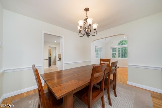 dining room featuring a chandelier, light wood-type flooring, and baseboards