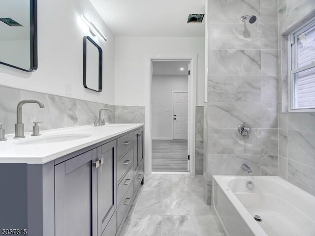 191 Matthew St, City Of Orange Twp, NJ 07050 - bathroom featuring marble look tile flooring, double vanity, tile walls, and shower / bathtub combination