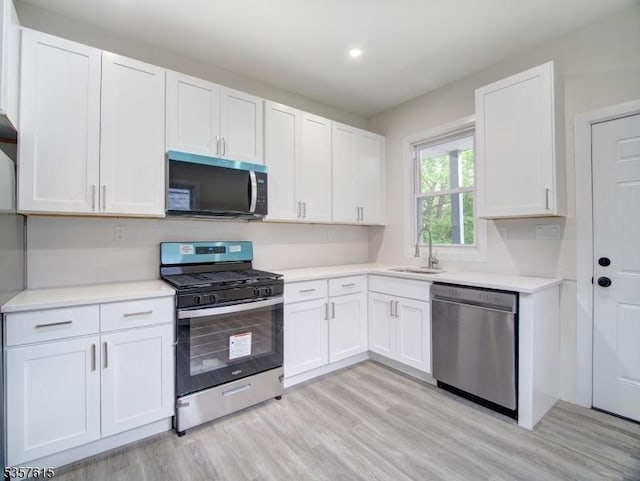 191 Matthew St, City Of Orange Twp, NJ 07050 - kitchen with appliances with stainless steel finishes, a sink, light countertops, white cabinetry, and light wood-type flooring