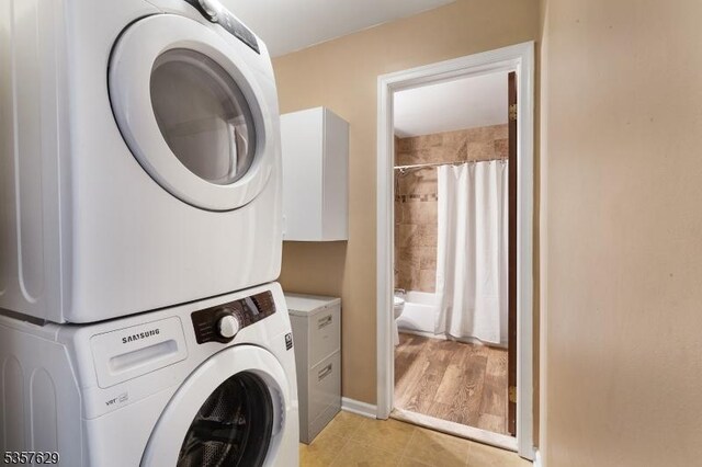 clothes washing area featuring stacked washer and clothes dryer and light tile patterned flooring