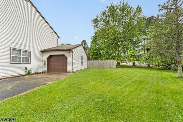 view of yard featuring asphalt driveway and an attached garage