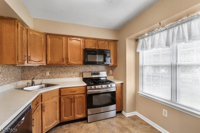 kitchen featuring appliances with stainless steel finishes, a sink, light countertops, tasteful backsplash, and baseboards