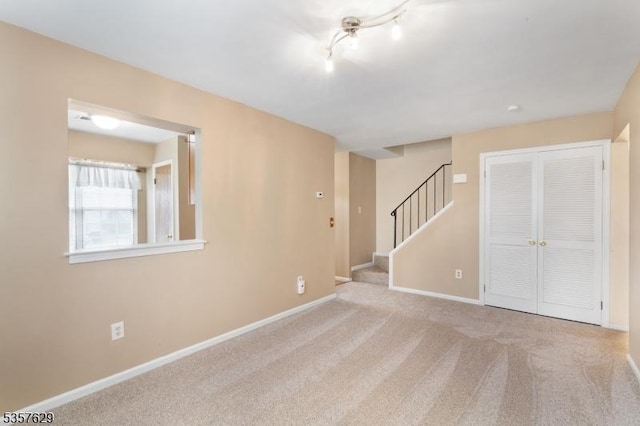 spare room with stairs, carpet flooring, and baseboards