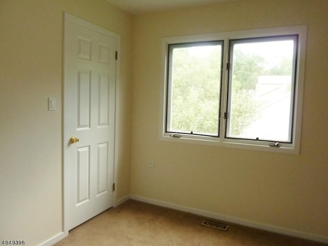 unfurnished room featuring light colored carpet and baseboards