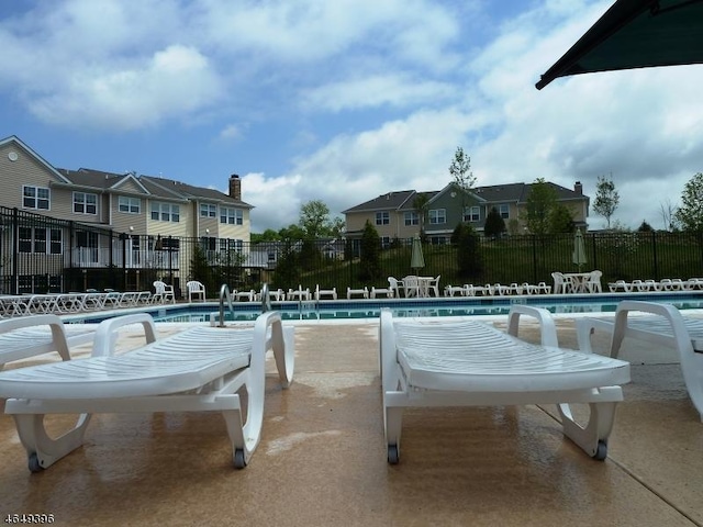 community pool with fence, a residential view, and a patio