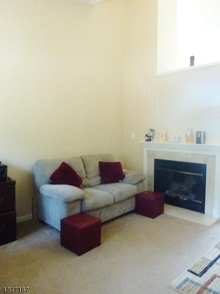 carpeted living area with a fireplace with flush hearth