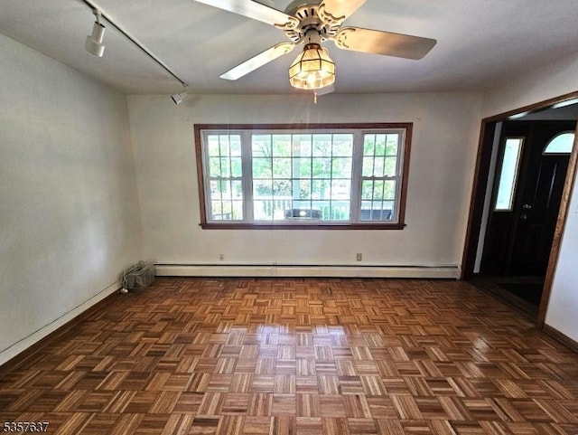 spare room featuring a baseboard radiator, rail lighting, a ceiling fan, and baseboards