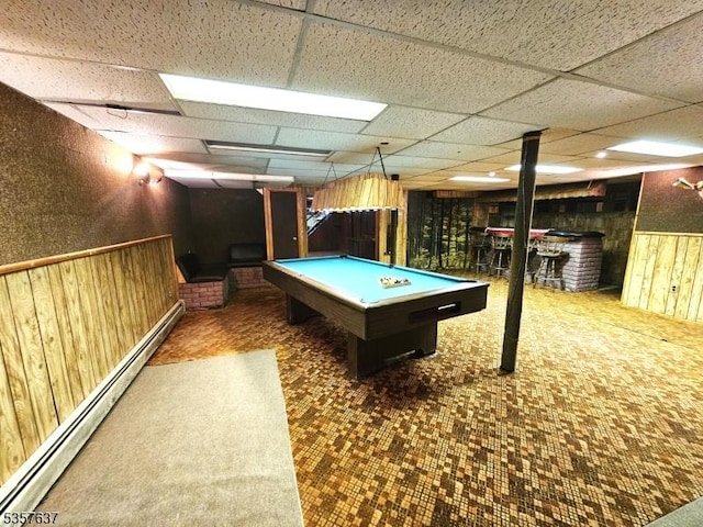 recreation room with billiards table, baseboard heating, wooden walls, and a drop ceiling