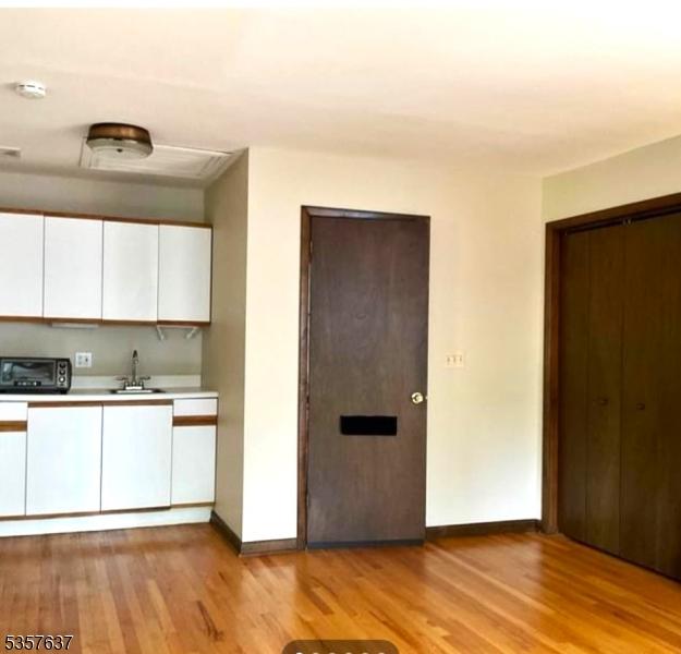 kitchen with a sink, light wood-type flooring, baseboards, white cabinets, and light countertops