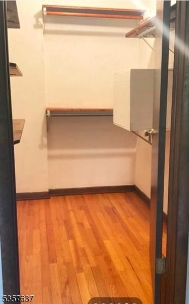 walk in closet with wood finished floors and a ceiling fan