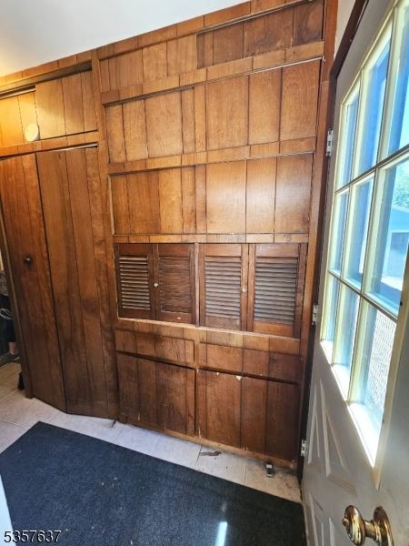 unfurnished room with plenty of natural light, tile patterned floors, and wooden walls
