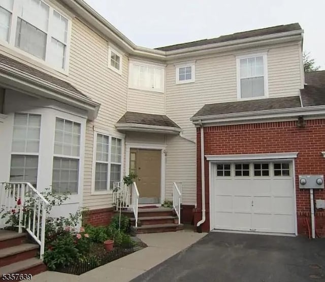 multi unit property featuring an attached garage, brick siding, and asphalt driveway