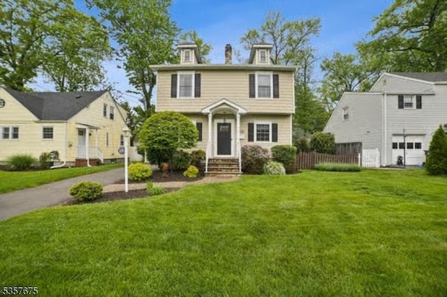 colonial-style house with an attached garage, a front lawn, and entry steps