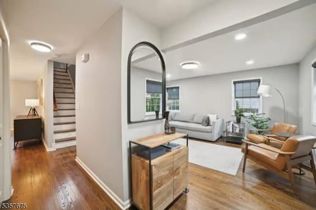 living area with wood finished floors, stairs, and baseboards