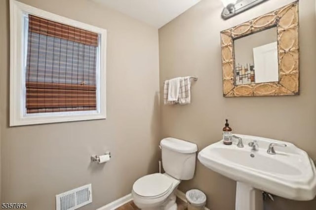 bathroom featuring toilet, baseboards, and a sink