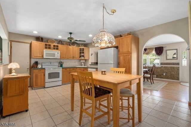 kitchen featuring white appliances, arched walkways, light tile patterned flooring, pendant lighting, and a ceiling fan