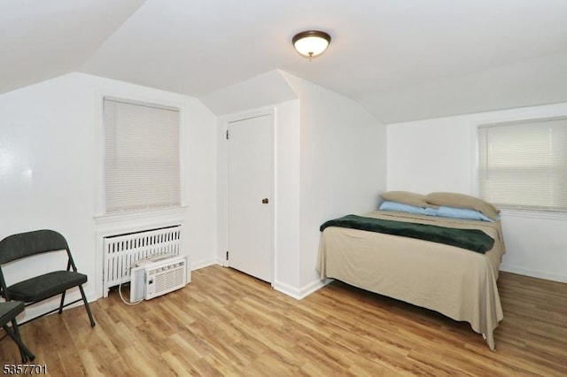 bedroom featuring vaulted ceiling, light wood-style flooring, baseboards, and radiator