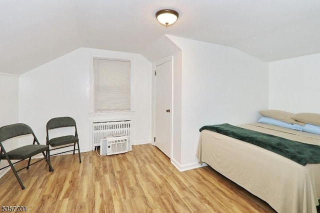 bedroom with lofted ceiling, light wood-style floors, baseboards, and heating unit