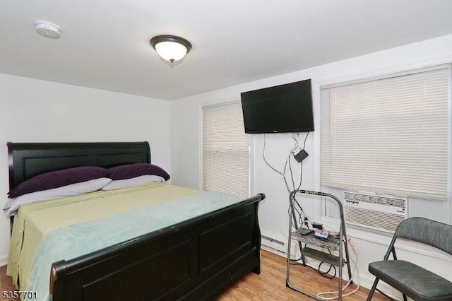 bedroom with light wood-style flooring, cooling unit, and a baseboard radiator