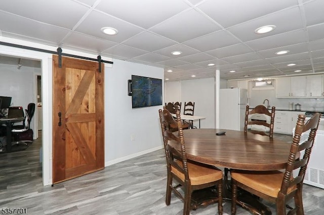 dining area with a barn door, recessed lighting, and baseboards