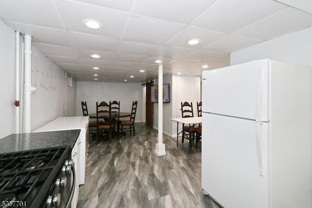 kitchen featuring freestanding refrigerator, stainless steel range with gas cooktop, recessed lighting, wood finished floors, and a paneled ceiling
