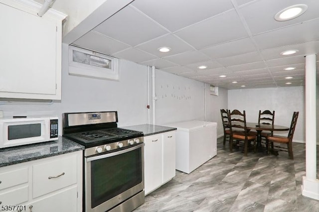 kitchen featuring stainless steel range with gas stovetop, white microwave, recessed lighting, refrigerator, and white cabinetry