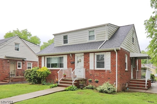 view of front of house featuring brick siding, a front yard, and roof with shingles