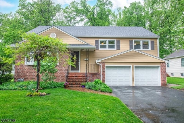 tri-level home featuring asphalt driveway, a front yard, and brick siding