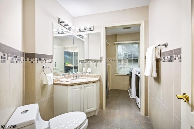 8 Sevell Cir Unit 8, Clark Twp, NJ 07066 - bathroom featuring tile walls, washer and clothes dryer, toilet, vanity, and a wainscoted wall