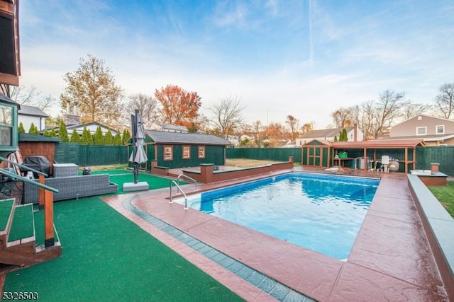 view of pool with an outbuilding, a fenced backyard, and a patio