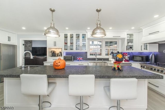 kitchen featuring a sink, backsplash, white cabinetry, custom range hood, and black microwave