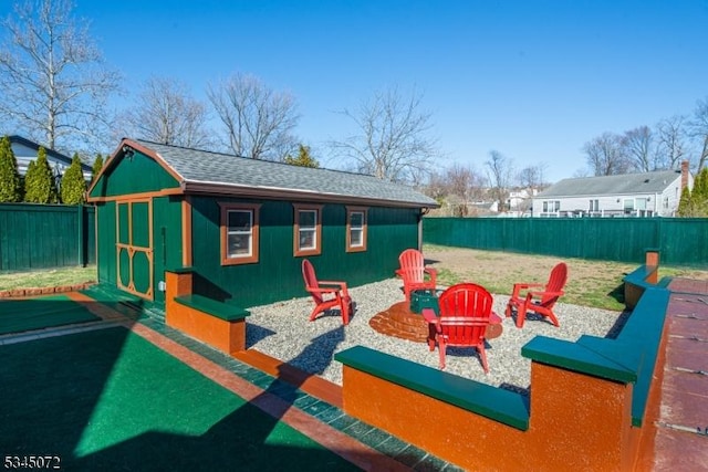 view of jungle gym with a fire pit, an outbuilding, and a fenced backyard