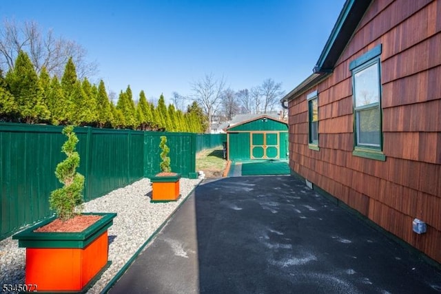 view of patio with an outdoor structure, a shed, and a fenced backyard