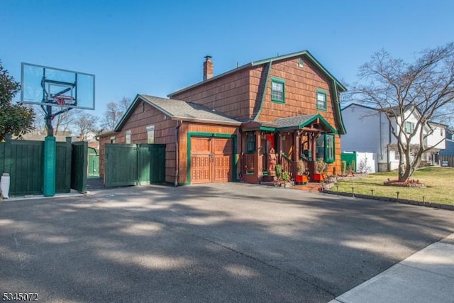 view of front facade with a chimney, fence, and a gambrel roof