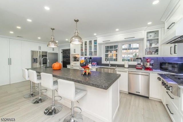 kitchen with appliances with stainless steel finishes, a sink, backsplash, white cabinetry, and recessed lighting