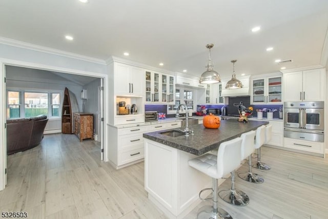 kitchen with oven, a sink, a warming drawer, crown molding, and plenty of natural light