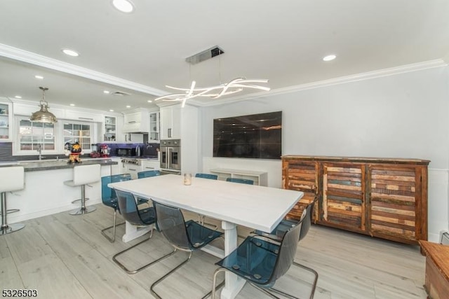 dining space featuring crown molding, light wood-type flooring, recessed lighting, and a chandelier