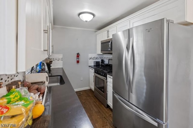 kitchen featuring appliances with stainless steel finishes, backsplash, white cabinets, dark wood-type flooring, and dark countertops