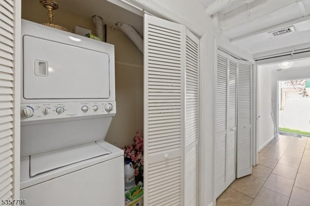 laundry room featuring stacked washer and clothes dryer and light tile patterned floors