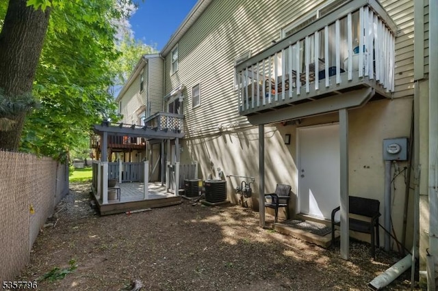 rear view of house featuring a balcony, fence, and central air condition unit