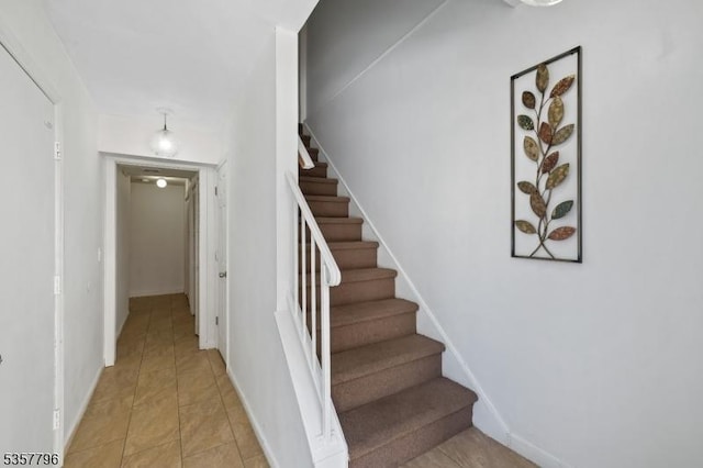 stairway featuring baseboards and tile patterned flooring