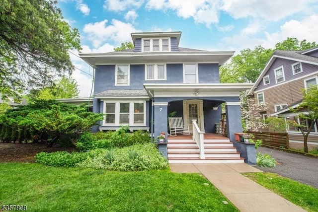 american foursquare style home with covered porch, stucco siding, and a front lawn