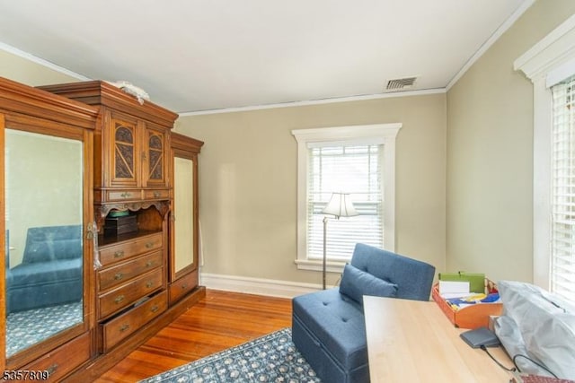 living area with wood finished floors, ornamental molding, and baseboards