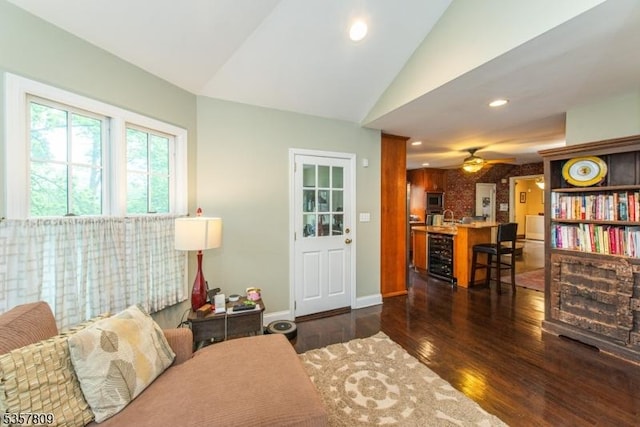 living area with beverage cooler, a bar, dark wood-type flooring, vaulted ceiling, and a ceiling fan