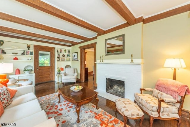 living area with beamed ceiling, wood finished floors, and a fireplace with flush hearth