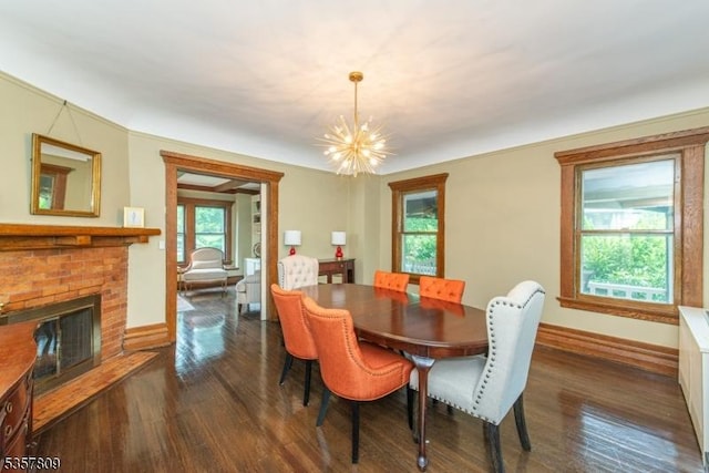 dining area with a chandelier, dark wood-style flooring, a brick fireplace, and baseboards
